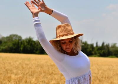 a woman in a white dress and hat in a wheat field