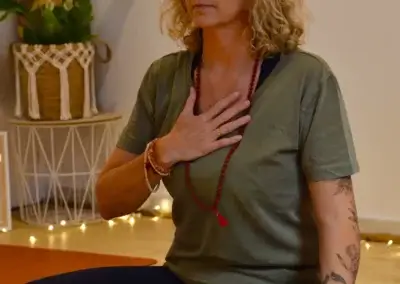 a woman sitting on a yoga mat with her hand on her chest