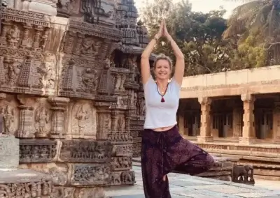 a woman standing on one leg in front of a stone building